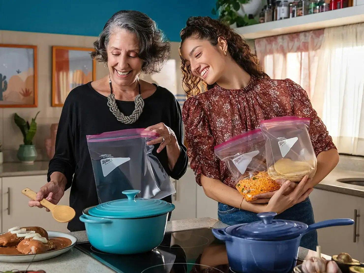 Two women cooking and holding ingredients in Ziploc bags